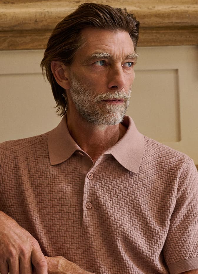 Middle-aged man with gray beard wearing a Brioni textured pink polo shirt, looking off to the side against a neutral background.