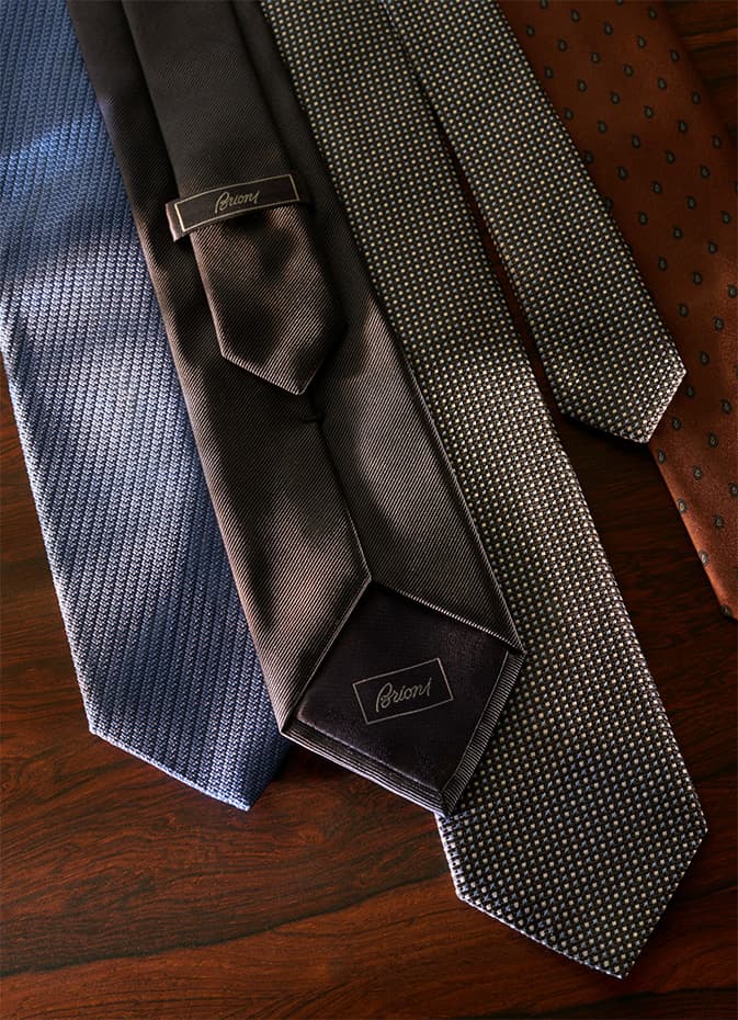Two dark blue Brioni perfume bottles with black caps displayed on weathered stone steps in warm lighting.