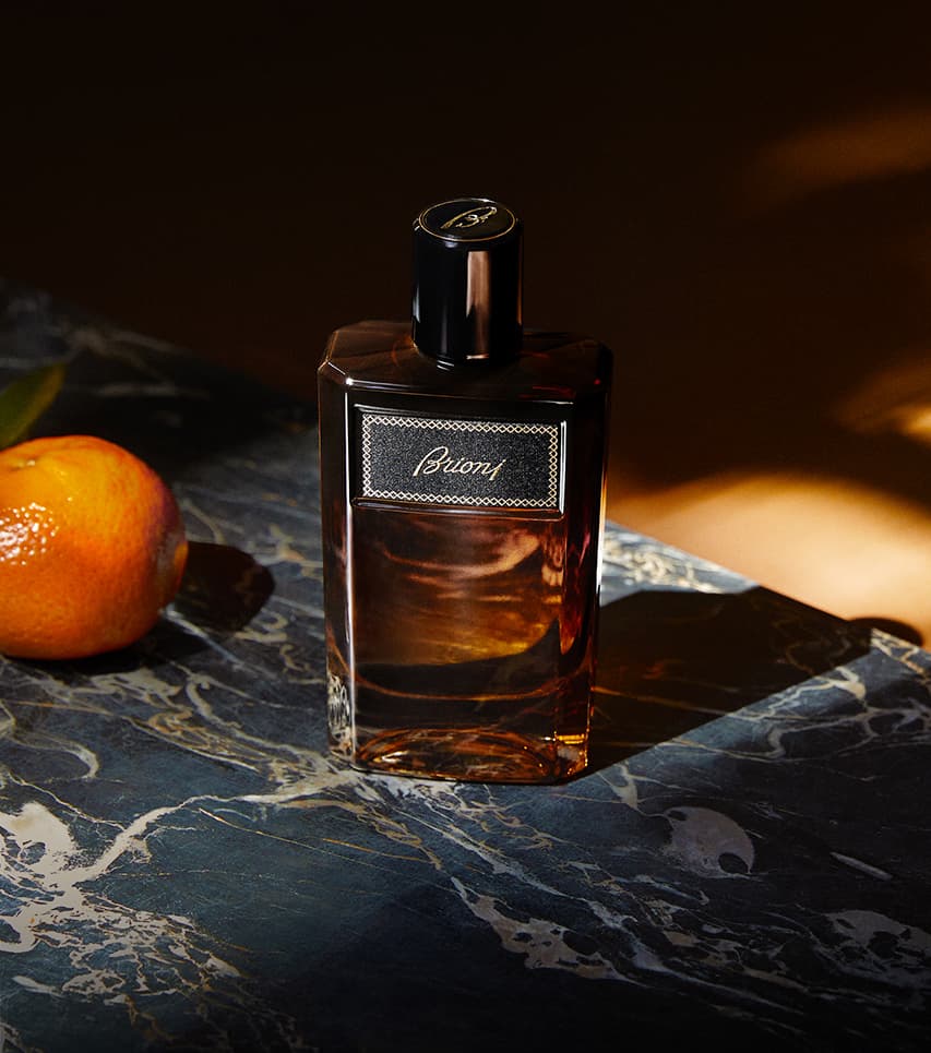 Elegant Suave brown bottle on dark marble surface with an orange fruit beside it in warm lighting.