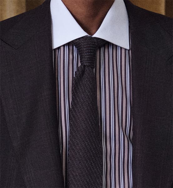 Dark Brioni suit with white collar, striped shirt, and textured black tie in formal business attire.