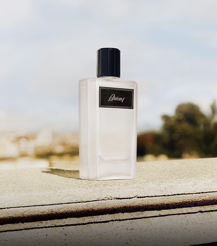 Elegant Eclat white bottle with black cap and gold label displayed on stone ledge against blurred outdoor background.