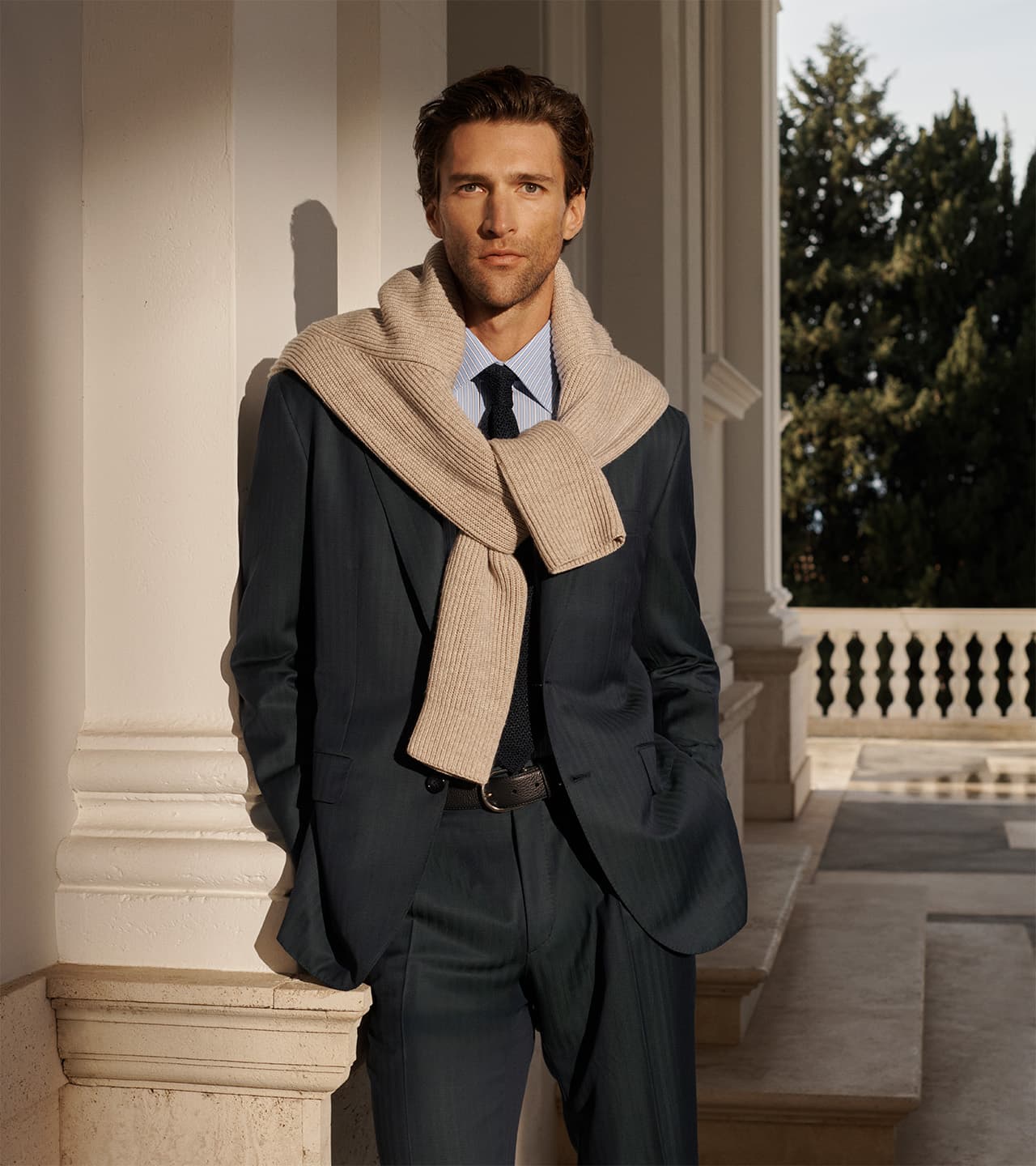 Close-up of Brioni rust-colored knit sweater showing textured fabric detail and ribbed cuffs with subtle embroidered logo.
