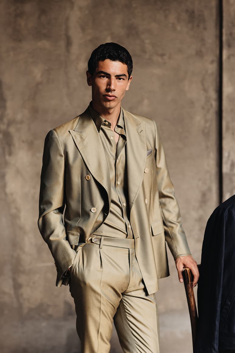 Model in elegant Olive Brioni suit and matching shirt from ss26 collection posing against a wall.